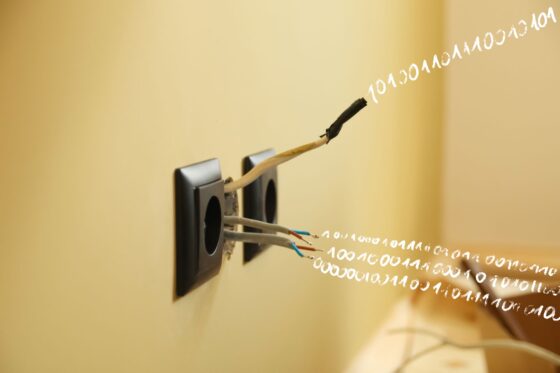 Foto von einer Steckdose an der Wand, aus der traurig ein paar abgerissene Kabel schauen